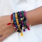 A close up of a woman's wrist and the seven bracelets she is wearing, each in a different color.