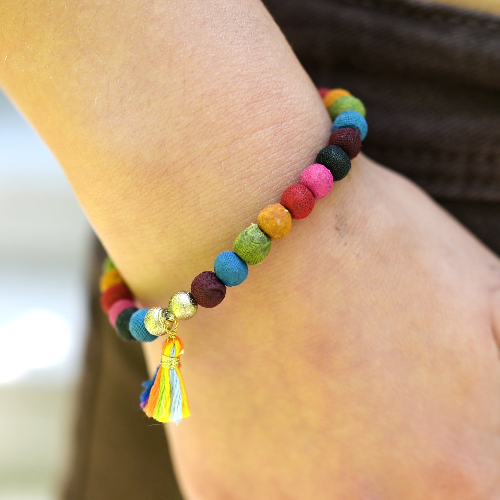 A close up of a woman's wrist and the rainbow beaded bracelet she wears.