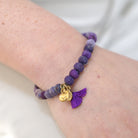 A close up of a woman's wrist and the purple beaded bracelet she wears.