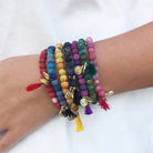 A close up of a woman's wrist and the seven bracelets she is wearing, each in a different color.